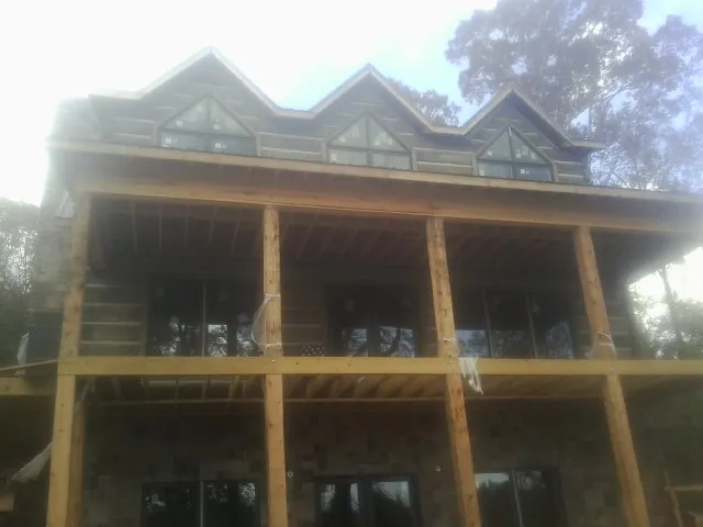 Dormers and porch framing on a large log home under construction — Roof Coating work by our crew in Boynton Beach