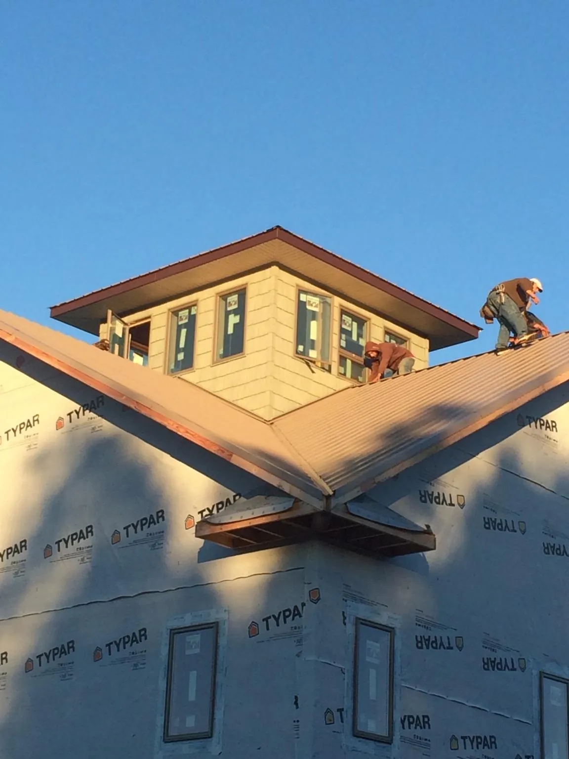 Roofers working around a rooftop cupola on a new metal roof at sunset — Roof Waterproofing in Boynton Beach by Roofing Brothers